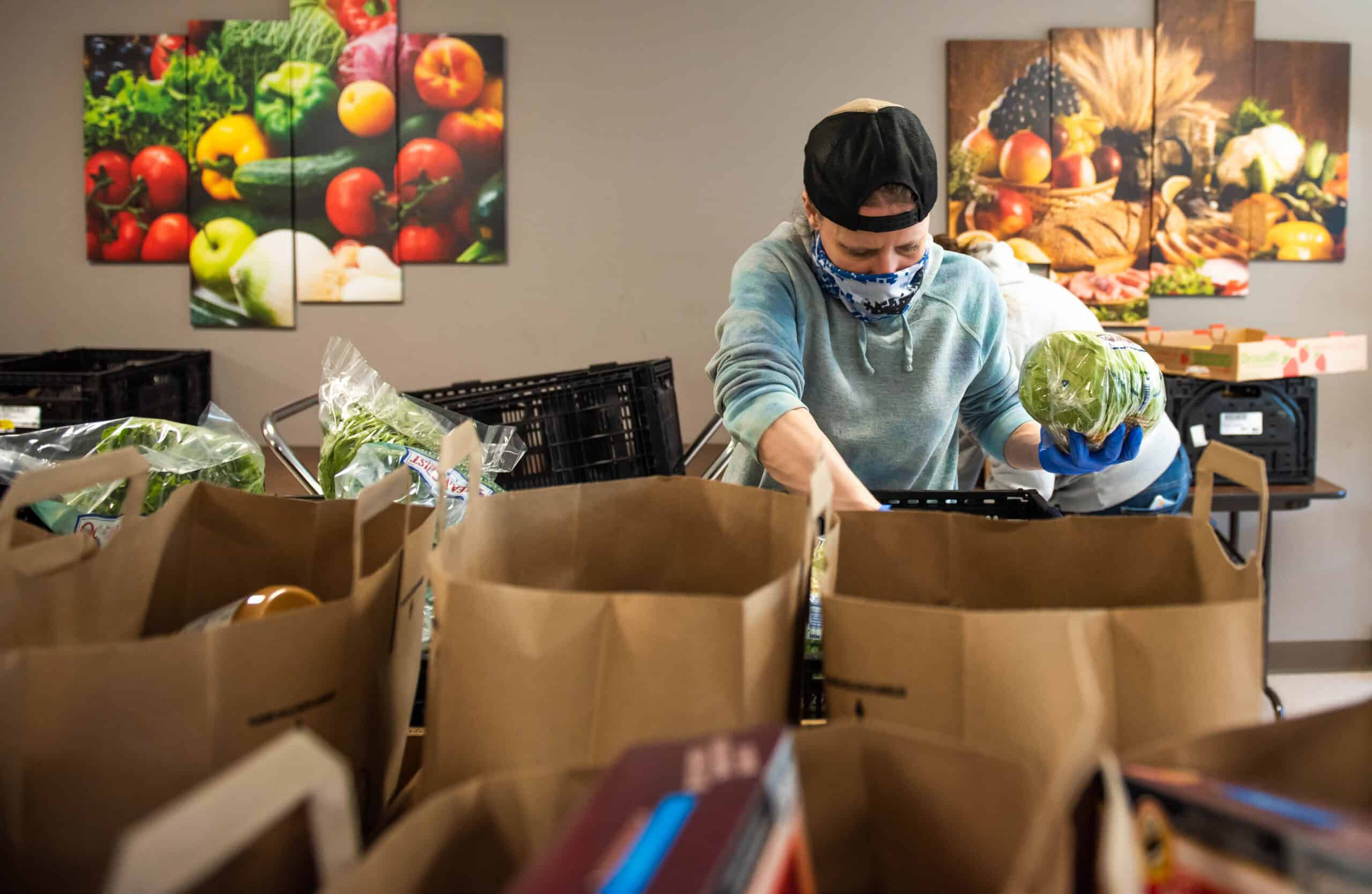 A food bank volunteer wearing a face mask loads up bags of groceries and produce for local families in Augusta, Maine.
