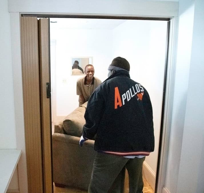 Two men move a piece of furniture into the Somali Bantu Community Association's new office, purchased with financing from Genesis.