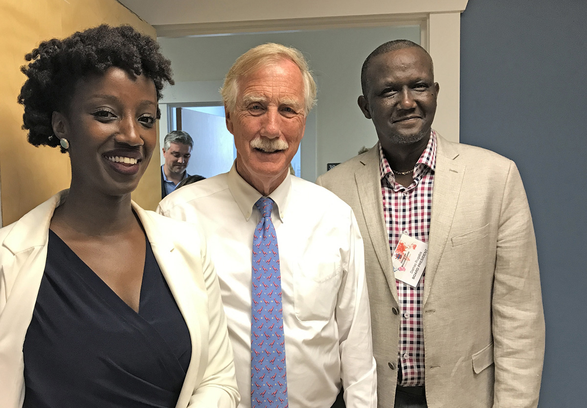 Three people smile at the camera while attending the grand opening of the Portland Immigrant Welcome Center: Genesis Board Member Shima Kabirigi, Maine Senator Angus King, and Damas Rugaba, the center’s board president.