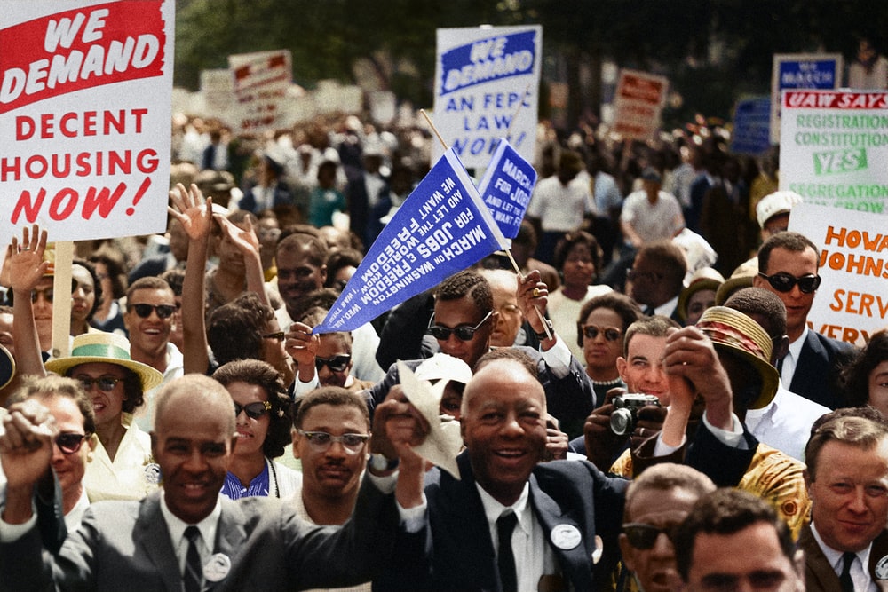 An historic image from the 1960's of a Civil Rights march, with participants hodling signs in support of decent housing.