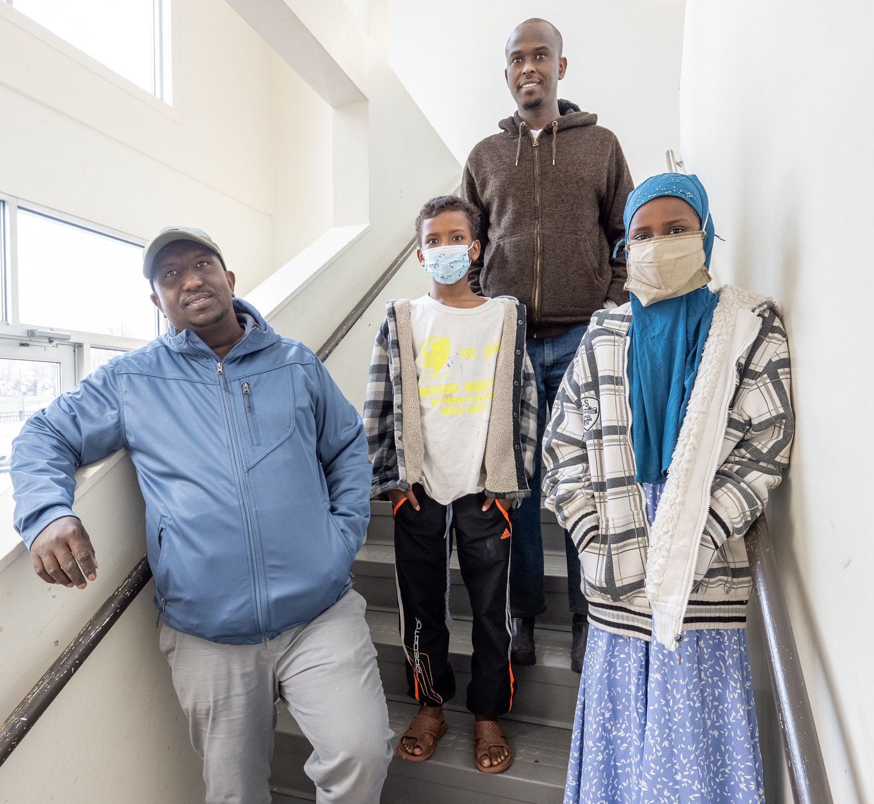 A property owner stands in the stairwell with a father and his children, residents of his Lewiston rental property purchased with a Genesis Fund fee-based loan created for Muslim borrowers who are prohibited from paying interest.
