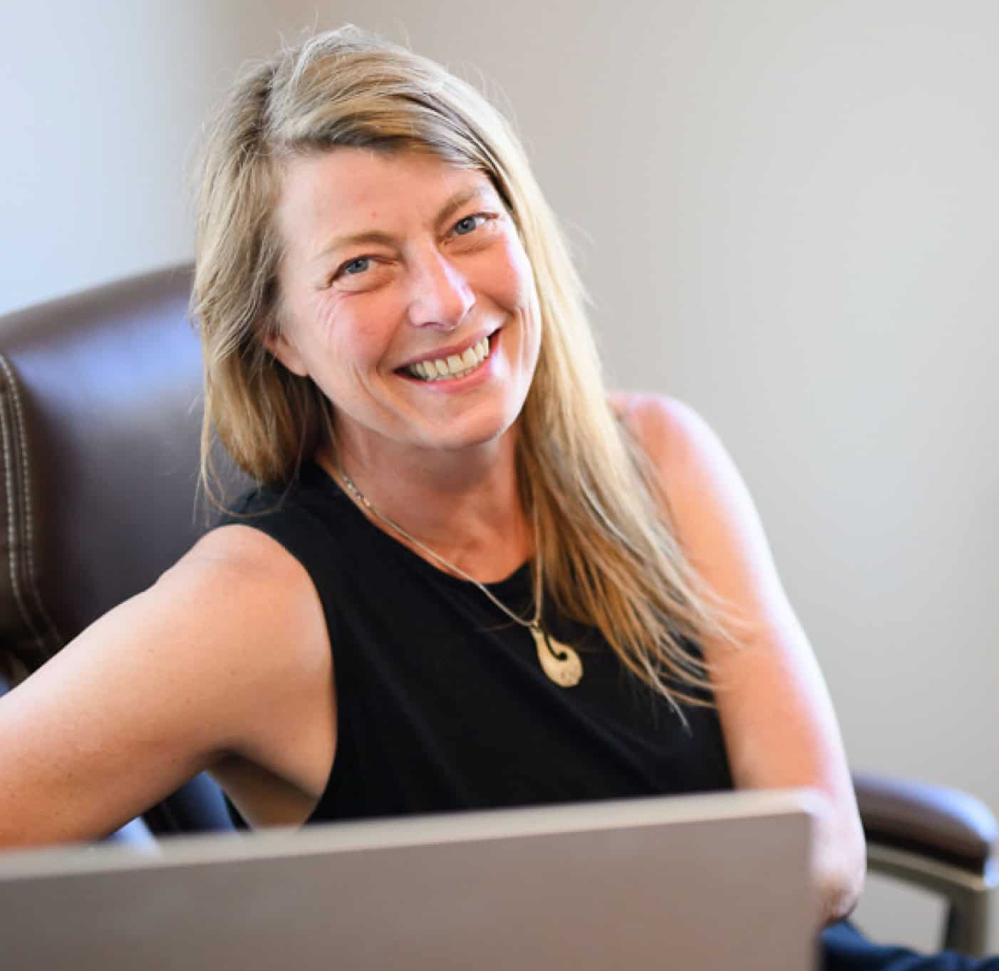 Smiling woman wearing black dress sitting behind computer at MaineStreet Business Building in Machias, Maine