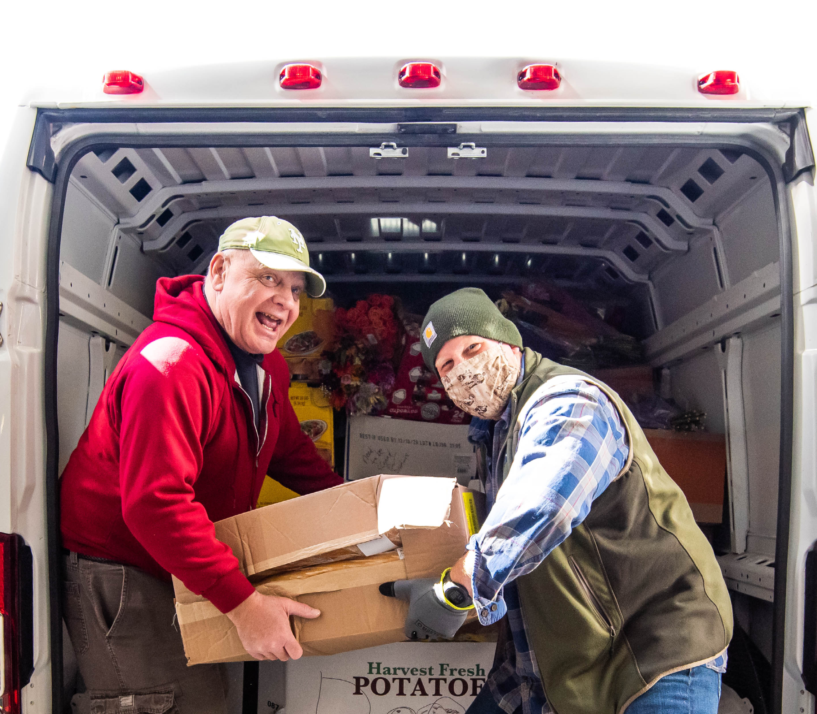 Two men who are food pantry volunteers unloading boxes from van