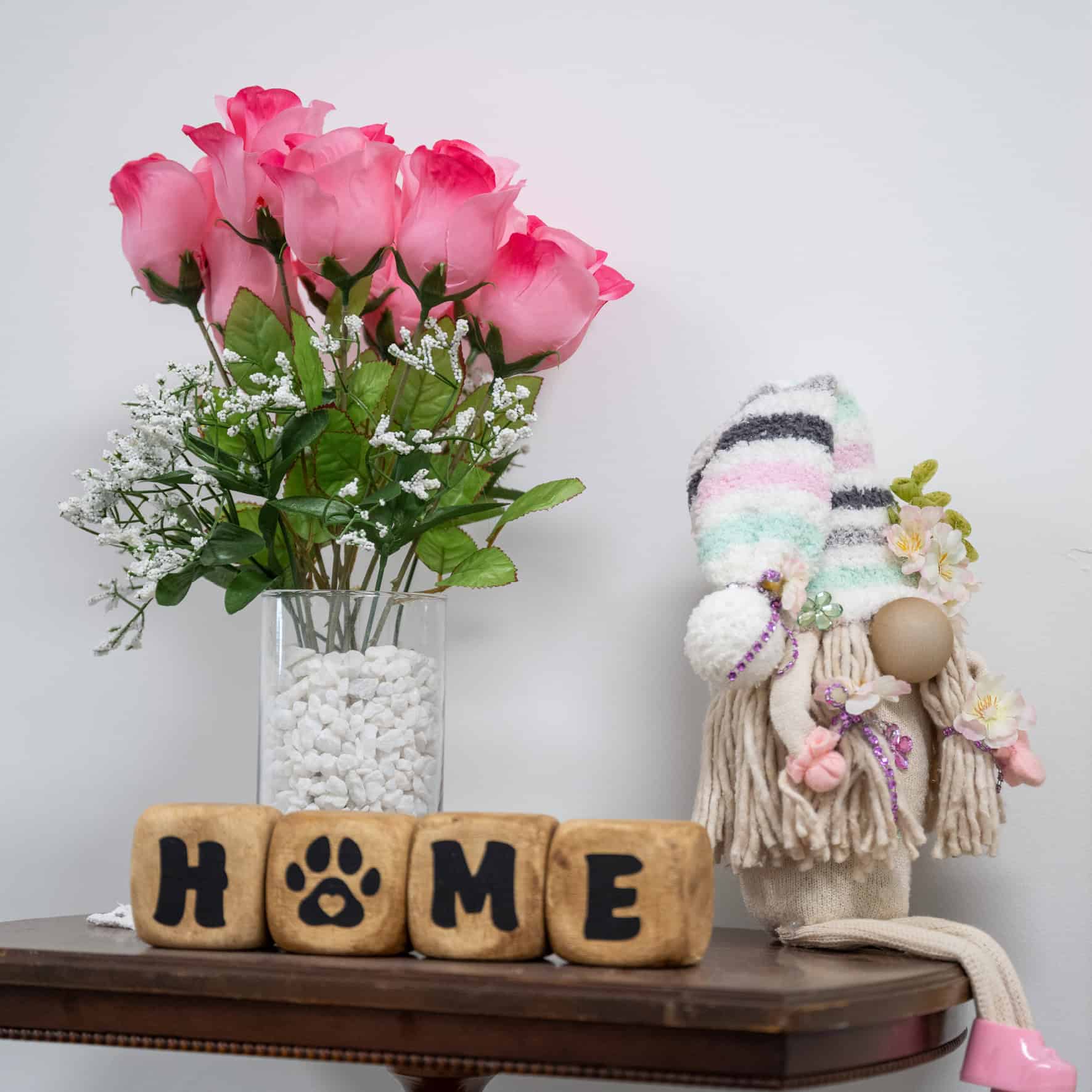 Decorative home decor with pink roses, a handmade doll, and wooden blocks spelling 'HOME'.