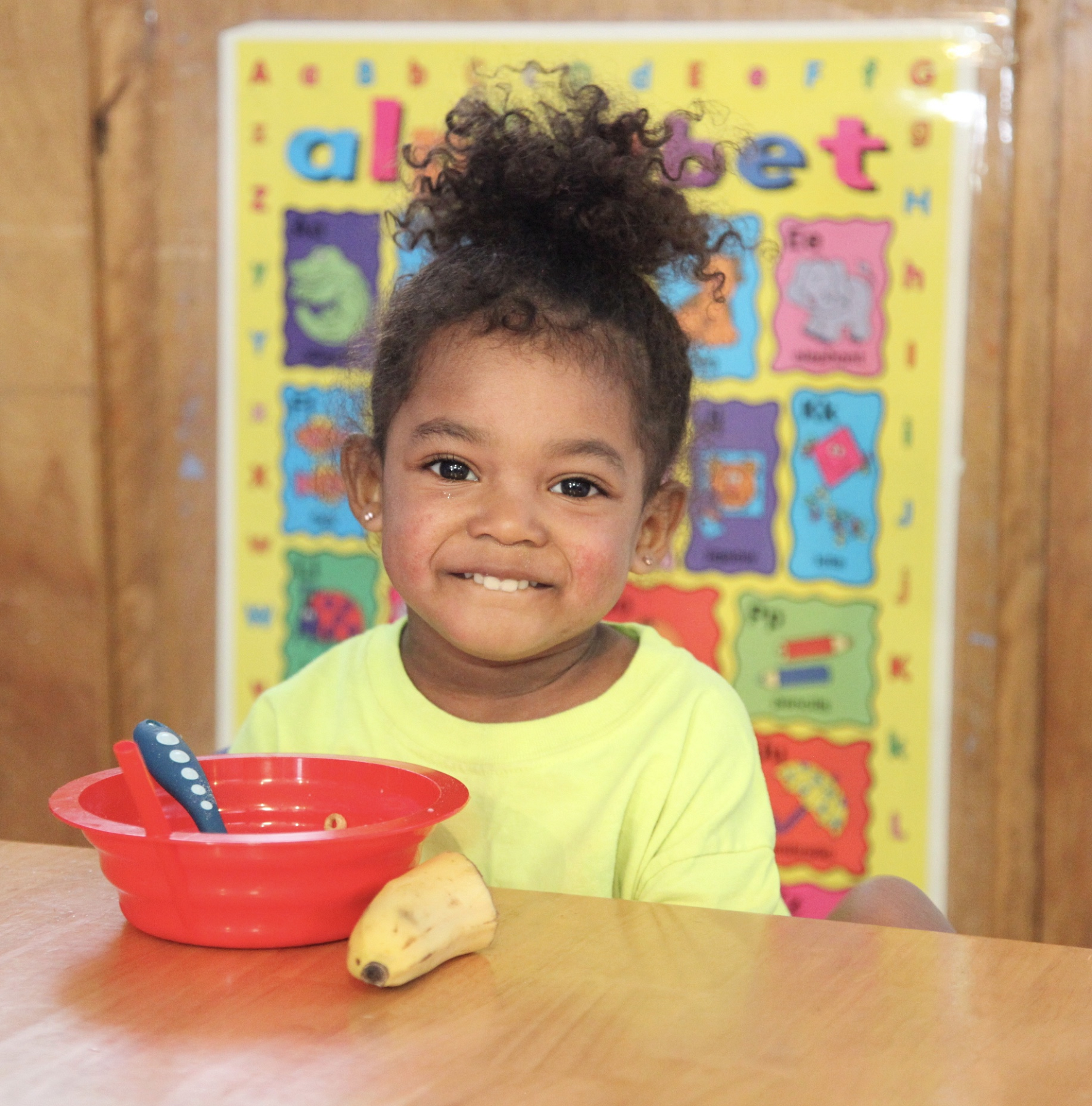 A preschooler smiles while she sits down to enjoy a healthy breakfast at Youth and Family Outreach in Portland, Maine.
