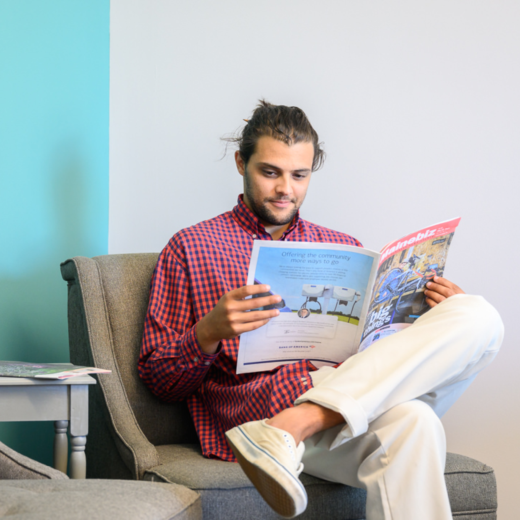 A young professional man reads an industry publication while sitting in the reception area of co-working office space at the MaineStreet Business Building in Machias.