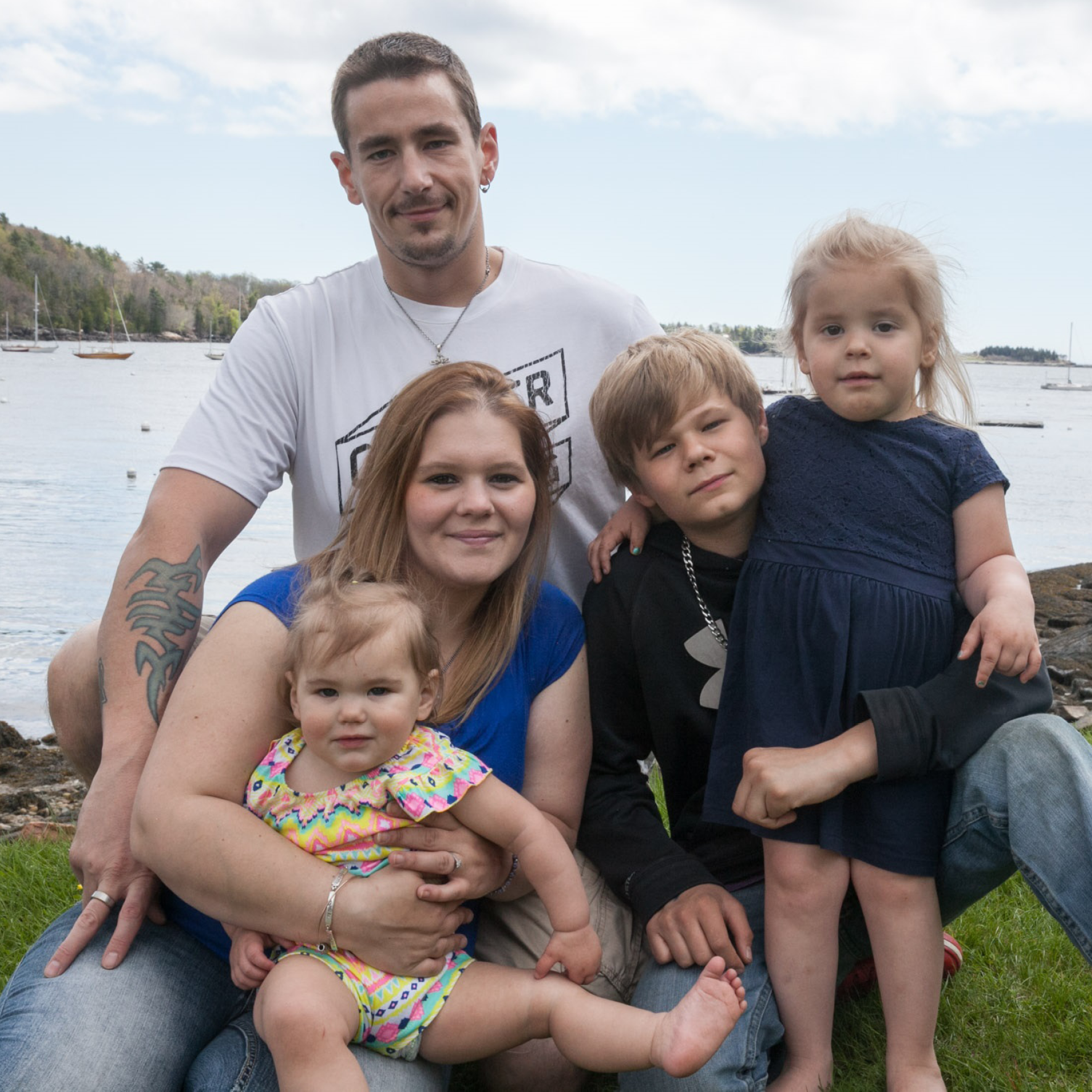 A young family poses by the shoreline in a coastal Maine community.