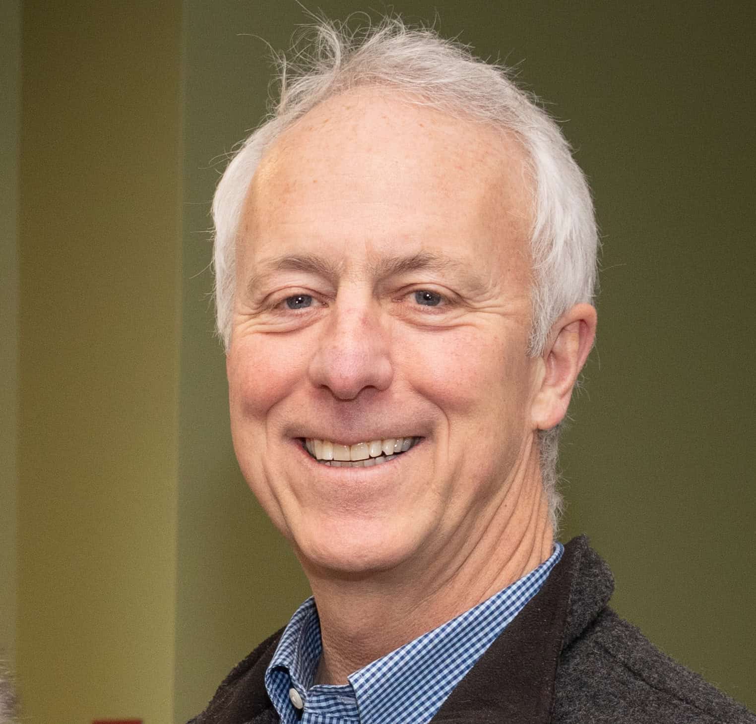 Smiling man with gray hair in professional setting.
