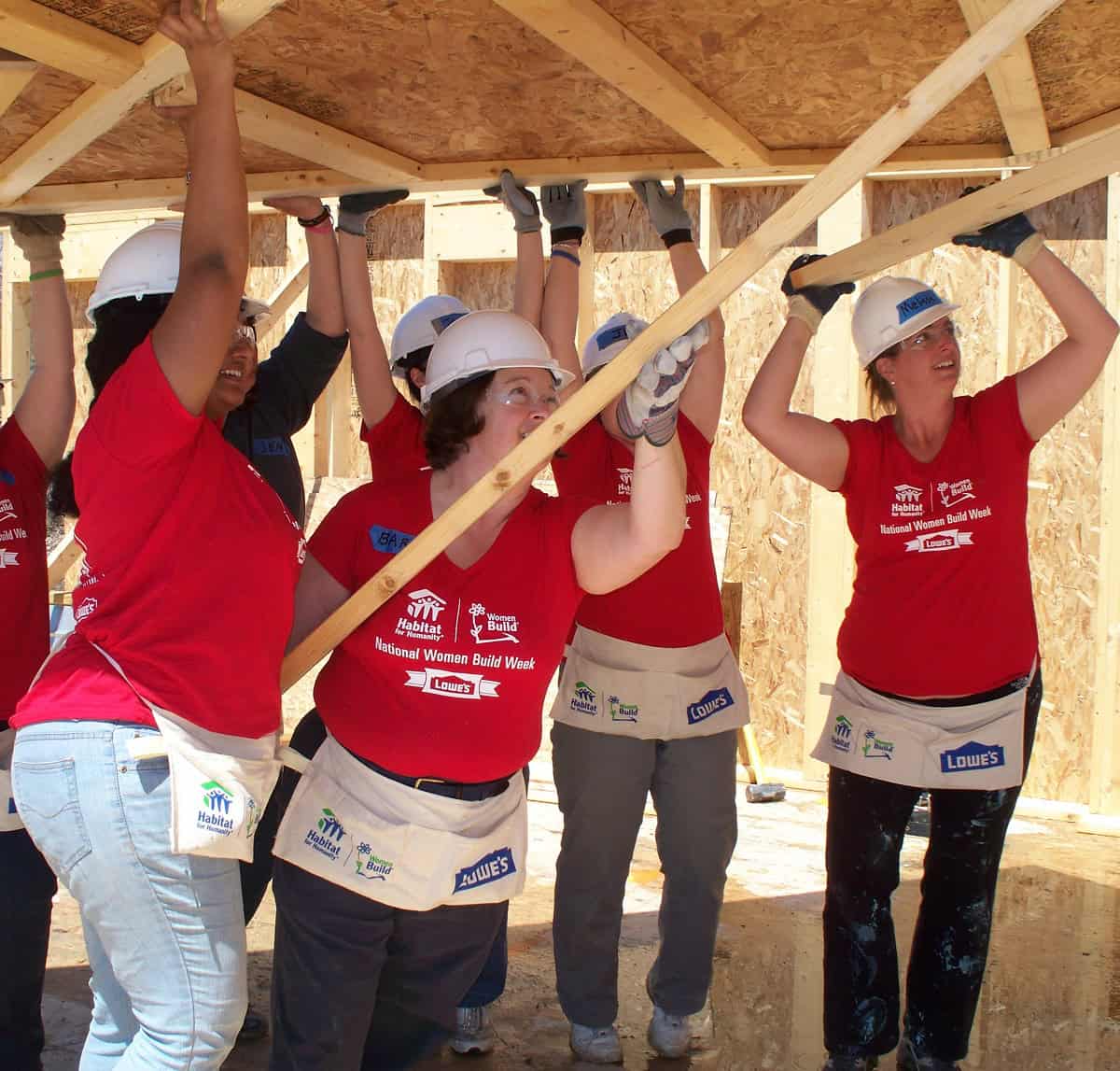 Women volunteers building a house with wooden beams at a Habitat for Humanity project.