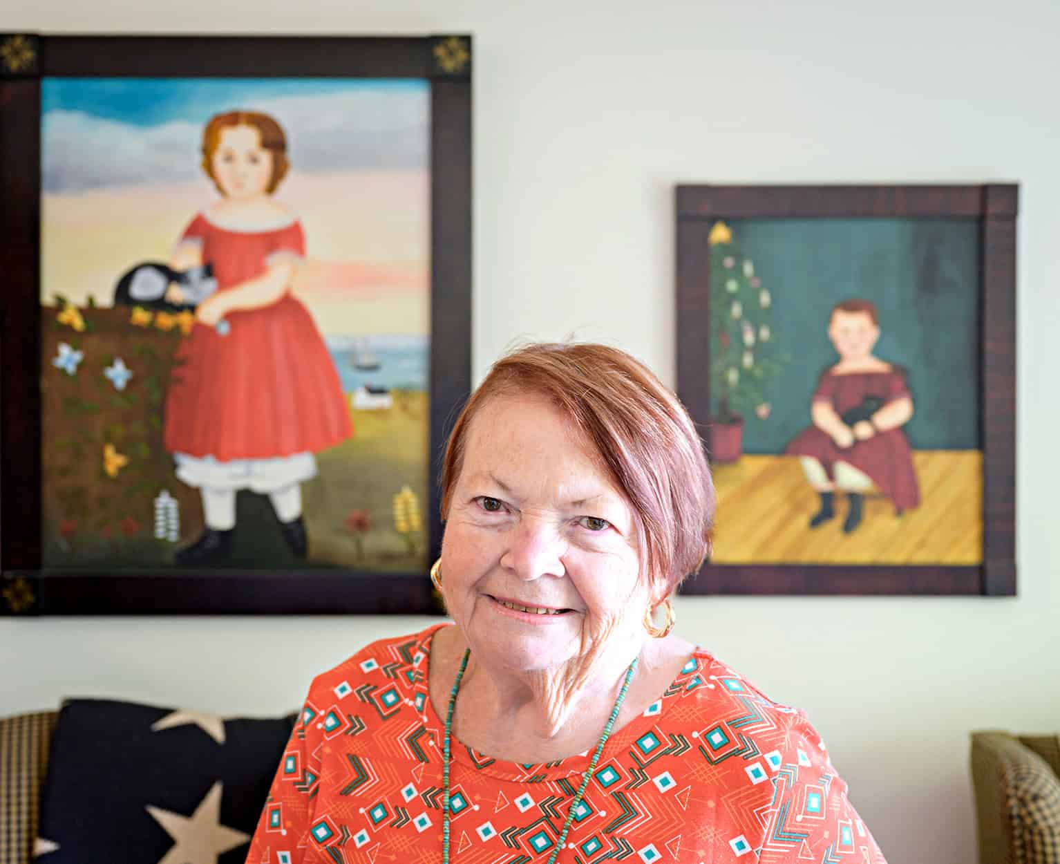 Smiling elderly woman in front of colorful artwork at The Genesis Fund event.