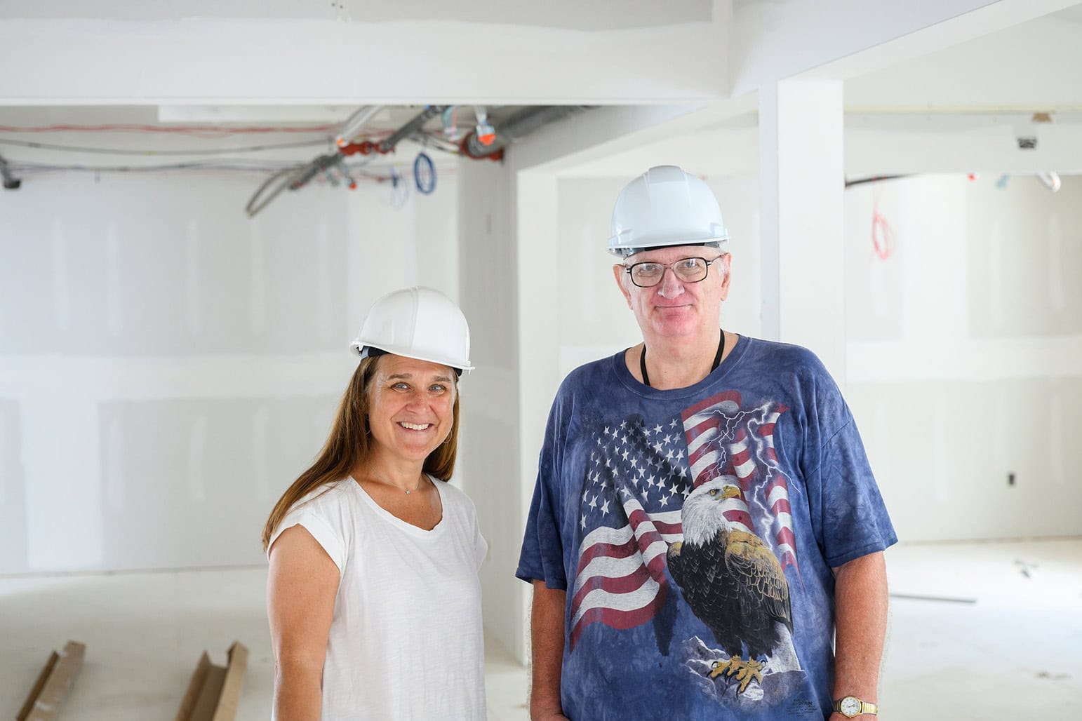 Two construction workers in a building under construction, wearing helmets.