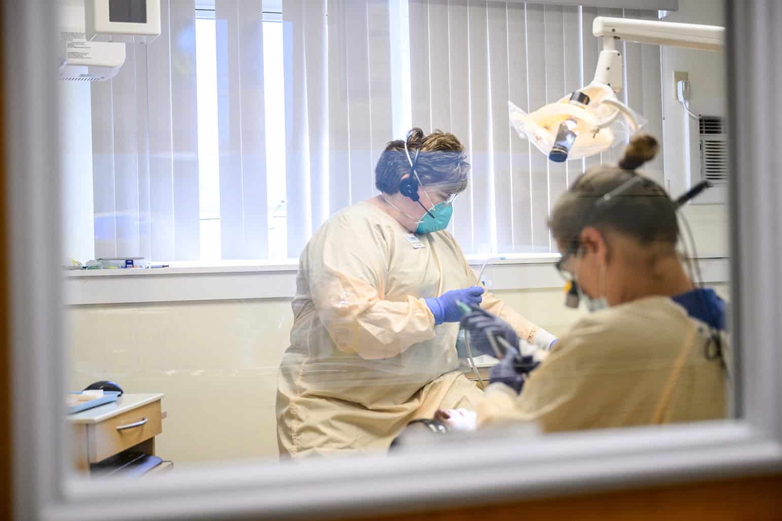Dental professionals performing a procedure in a clinical setting.