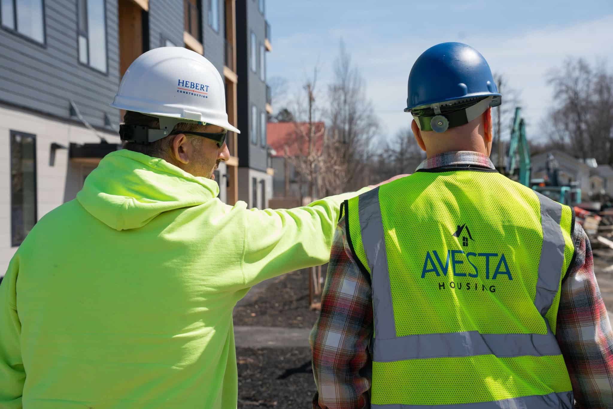 two construction workers wearing yellow jackets, with one that says Avesta