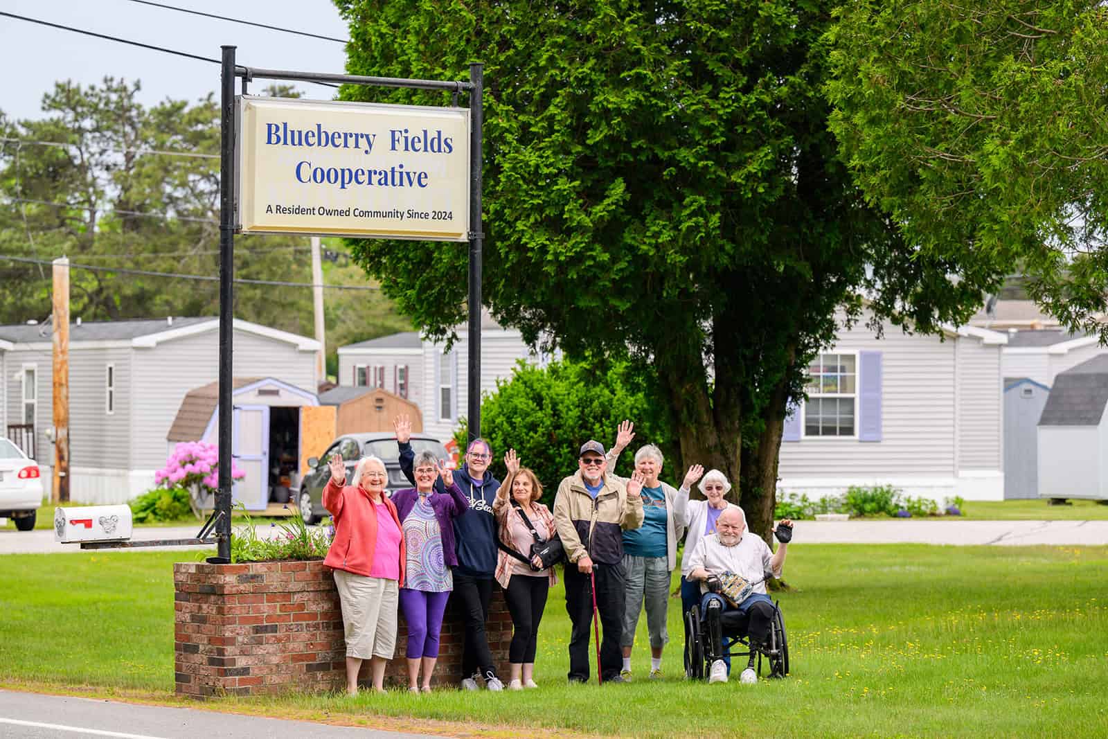 Group of diverse people standing near Blueberry Fields Cooperative sign.