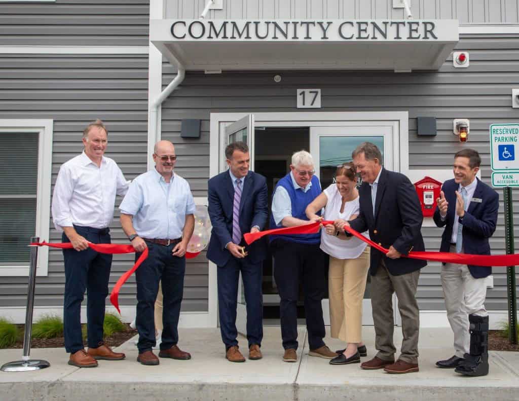 Community center ribbon-cutting ceremony with officials and staff outside.